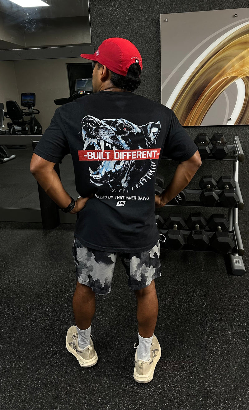 Person wearing a black t-shirt with a graphic design and text in a gym setting.